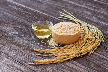Rice bran oil extract with paddy and brown rice isolated on rustic wooden table background.