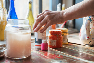 Female artist folding her paints at the table before the drawing in the art studio