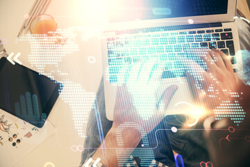 Multi exposure of man's hands typing over computer keyboard and world map hologram drawing. Top view. Technology concept.
