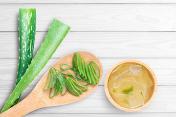 Aloe vera plant with cut slice and cube gel in wooden bowl isolated on gray wood table background. Top view. Flat lay. Copy space.