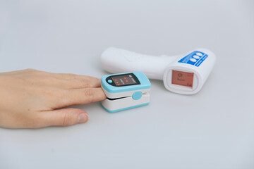 Pulse oximeter and thermometer gun on white background. Infrared isometric thermometer gun to check...
