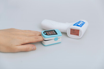 Pulse oximeter and thermometer gun on white background. Infrared isometric thermometer gun to check body temperature for virus symptoms. Measuring oxygen saturation, pulse rate and oxygen levels.