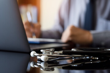 Doctor writing prescription, work on laptop computer at office.