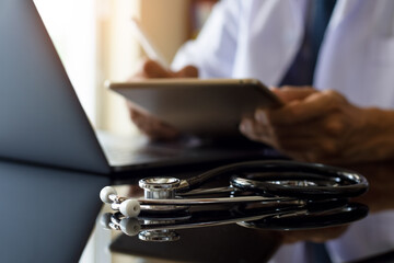 Doctor working on digital tablet computer at office.