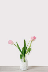A bouquet of three pink tulips stands in a glass vase with lace. The concept of the spring festival