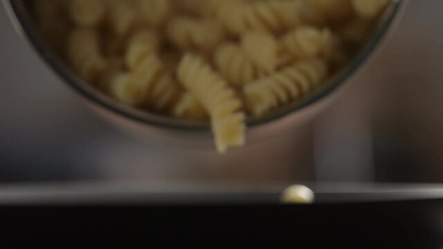 Slow motion fusilli poured on black plate