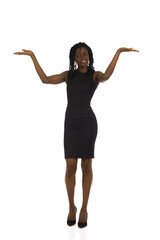 Young black woman in mini dress is standing with arms raised and presenting.