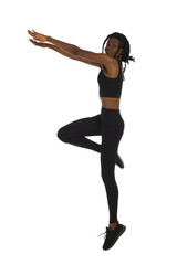 African woman in black sports clothes is jumping with arms outstretched. Side view.