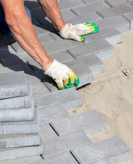 A worker is laying paving slabs in the yard. Construction