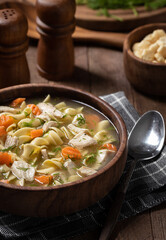 Bowl of chicken noodle soup on a wooden table - 473133638