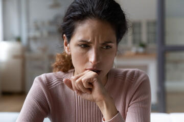 Fototapeta na wymiar Close up thoughtful upset woman thinking about problems sitting alone, pensive unhappy frustrated young female lost in thoughts, feeling lonely and depressed, suffering from divorce or break up