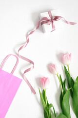 A bouquet of pink tulips, a gift box with a pink bow and a pink bag on a white background. Concept of Valentine's Day, Mother's Day, Birthday and Spring