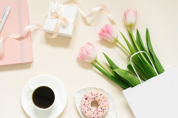 Tulips, gift box and coffee on a beige background. Flat lay. 8 March, International Women's Day. Valentine's Day.