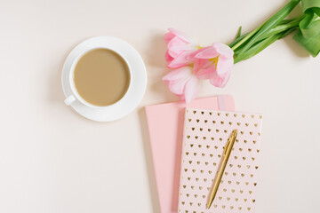 Female workspace with pink tulip flowers, diary, cup of tea and donut on beige background. Flat...