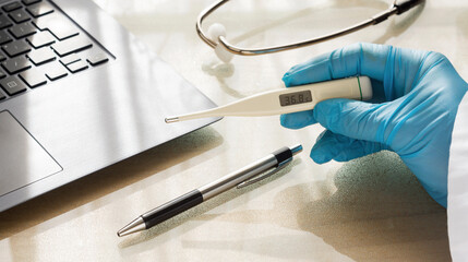 A doctor's hand holding a thermometer. A hand with glove  holding a thermometer and checking the temperature value 
