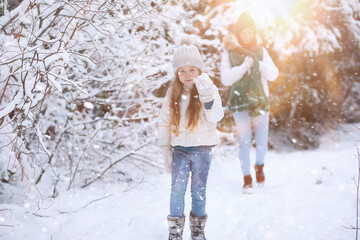 Young family for a walk. Mom and daughter are walking in a winter park.