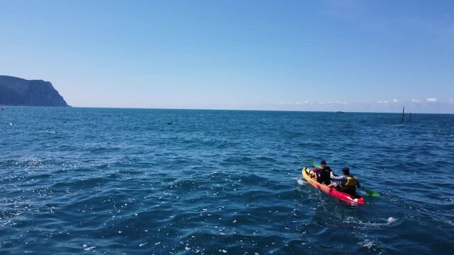 Kayak on sea. Aerial view. Couple sailing on a boat and paddling. Stock footage. A young couple of tourists on an active water vacation floats on the sea waves in a canoe or kayak. Summer and blue