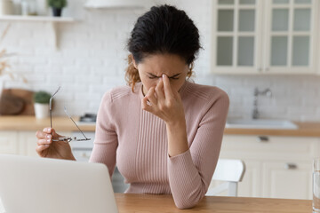 Close up tired woman taking off glasses, feeling eye strain after long hours computer work,...