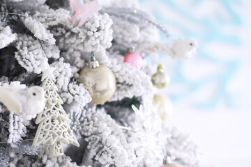 Christmas holiday background. Silver and color bauble hanging from a decorated on tree with bokeh and snow, copy space.