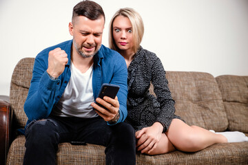 Young couple using smartphone, broken mobile phone, looking at screen, having financial problem, negative, worried, insufficient funds, reading bad news, hand on shoulder, mobile banking, messaging