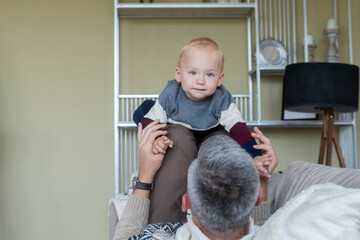 A happy father is having a good time with a charming son close-up, the family is having fun at home, a smiling dad hugs a little boy, plays a game, enjoys the weekend, having fun together