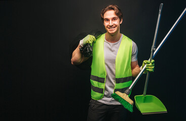 Smiling cleaner hold rubbish bag, broom and scoop