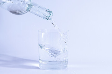 Pour water from the bottle into a glass. Isolated on white background.