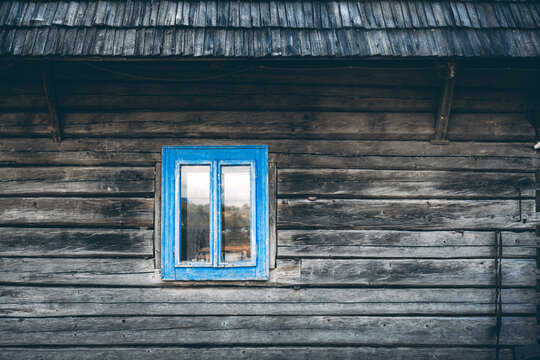 Wooden house wall with wooden roof and cyan blue window on old ukrainian house