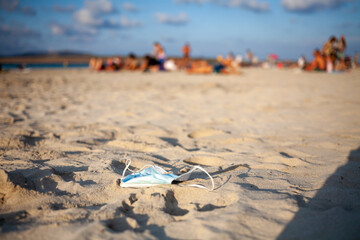 Pollution by disposable medical mask on beach by sea due coronavirus pandemic.