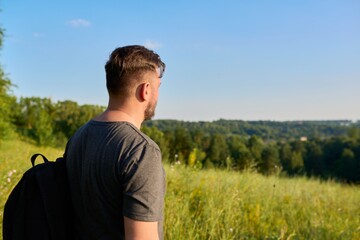 Middle-aged bearded man with a backpack on a hike looking at the horizon