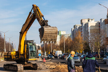 An excavator in a modern city is carrying out work during the reconstruction of the road. Repairs...