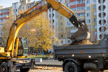 An excavator in a modern city is carrying out work during the reconstruction of the road. Repairs...