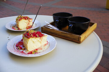 Two creamy cheesecake with peanut pieces on it, and two cups of coffee