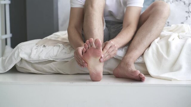 Foot pain, man suffering from feet ache and does self-massage, podiatry concept