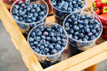 Blueberries in plastic cups. Trade in berries on the market. Close-up