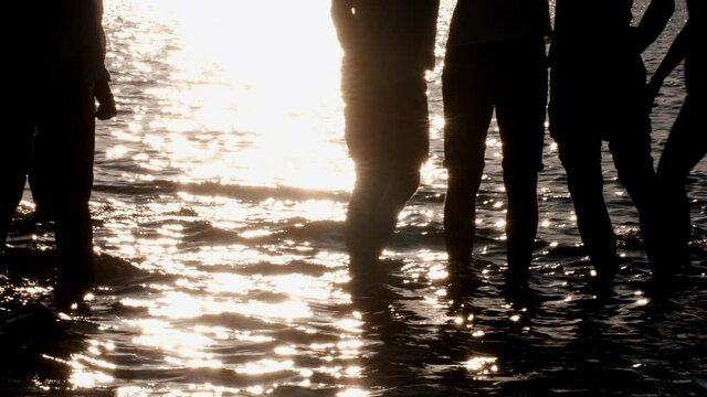 Group of seven Teenage Girls Dancing In The Water At The Beach At Sunset