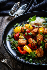 Fried chicken nuggets with white rice, bell peppers and parsley on wooden table