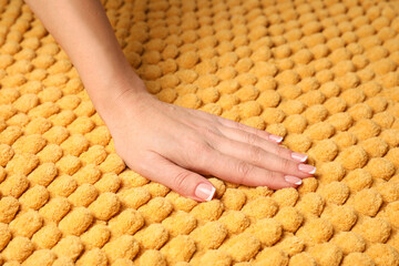 Woman touching soft yellow fabric, closeup view