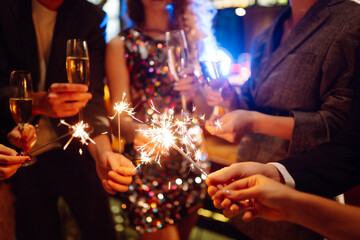 Sparkling sparklers in the hands of young friends. People  celebrate winter holidays with sparkles...