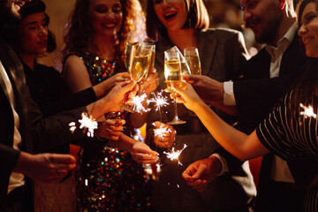 Sparkling sparklers in the hands of young friends. People  celebrate winter holidays with sparkles...