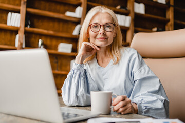 Confident middle-aged caucasian CEO mature businesswoman freelancer leader working on distance on...