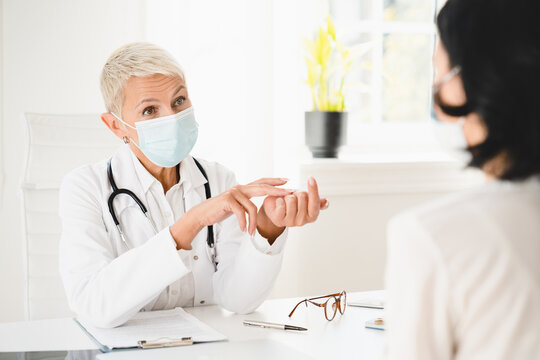 Senior Female Doctor Gynecologist In Protective Face Mask Against Coronavirus Covid 19 Talking With Patient About Diagnosis Recovery, Giving Prescriptions Test Results In Hospital