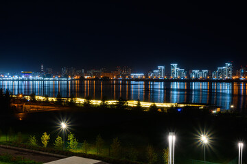Fototapeta premium Illuminated buildings on the river bank