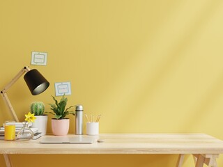 Working room with laptop and working equipment next to the yellow wall.