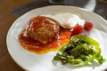 お皿の上のハンバーグと野菜と目玉焼き