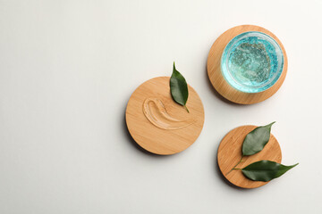 Flat lay composition with blue cosmetic gel and leaves on white background. Space for text
