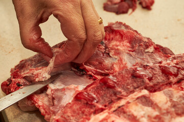 Przygotowywanie i dzielenie surowego wieprzowego mięsa domowym sposobem w kuchni - obrazy, fototapety, plakaty
