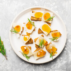 Delicious appetizer, tapas. Parmesan cheese slices on crispy toast with tangerine orange jam and rosemary.