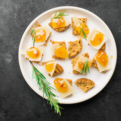 Delicious appetizer, tapas. Parmesan cheese slices on crispy toast with tangerine orange jam and rosemary.