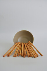 Korean sesame seed sticks leaning on a bowl against white background